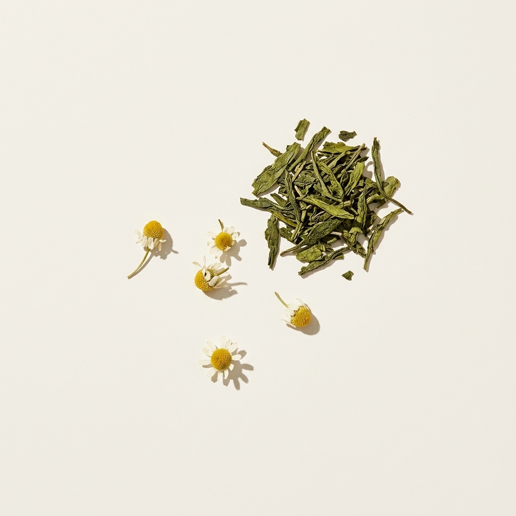 Chamomile flowers and green tea leaves on a bone surface